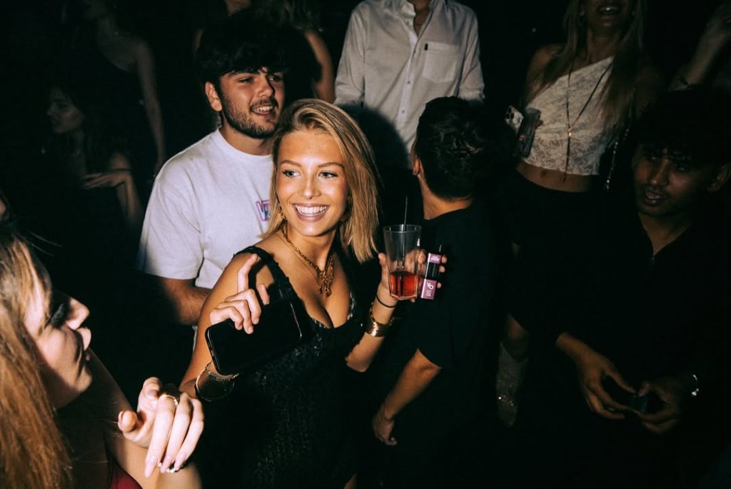 A girl holding a drink and laughing during a party at Funky Buddha club in London.